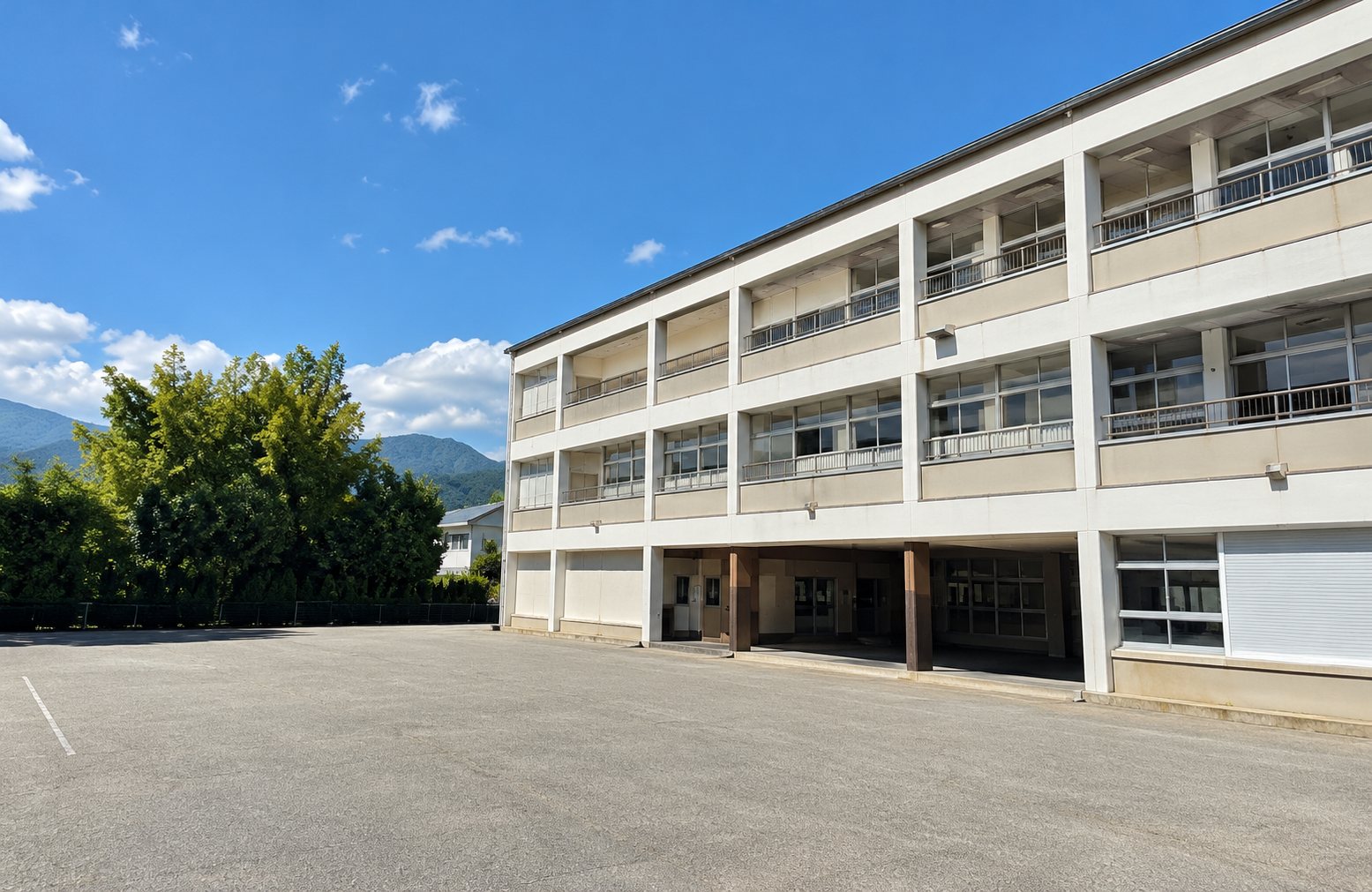 Bâtiment du groupe scolaire Maché à Chambéry, balcons et parking sous un ciel bleu.